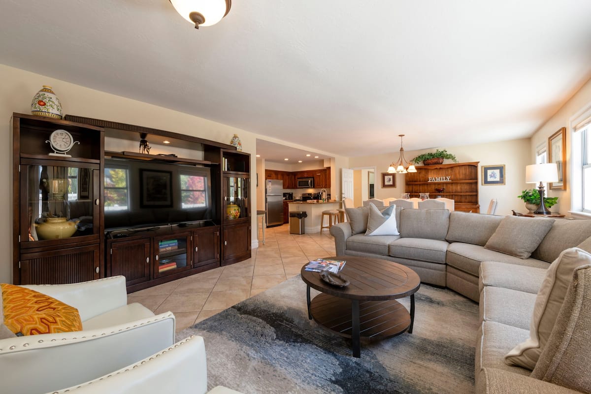 A modern living room with a sectional sofa, a coffee table, and a TV in a wooden entertainment unit.
