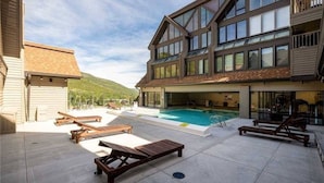 Ein zweistöckiges Gebäude mit Swimmingpool, Außenbereich und Blick auf die Berge.