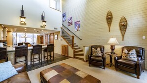 A spacious living area with a large couch, two leather armchairs, a coffee table, and a staircase leading to an upper level. - Park Avenue Upgraded 2 Bedroom Condominiums (Park City)