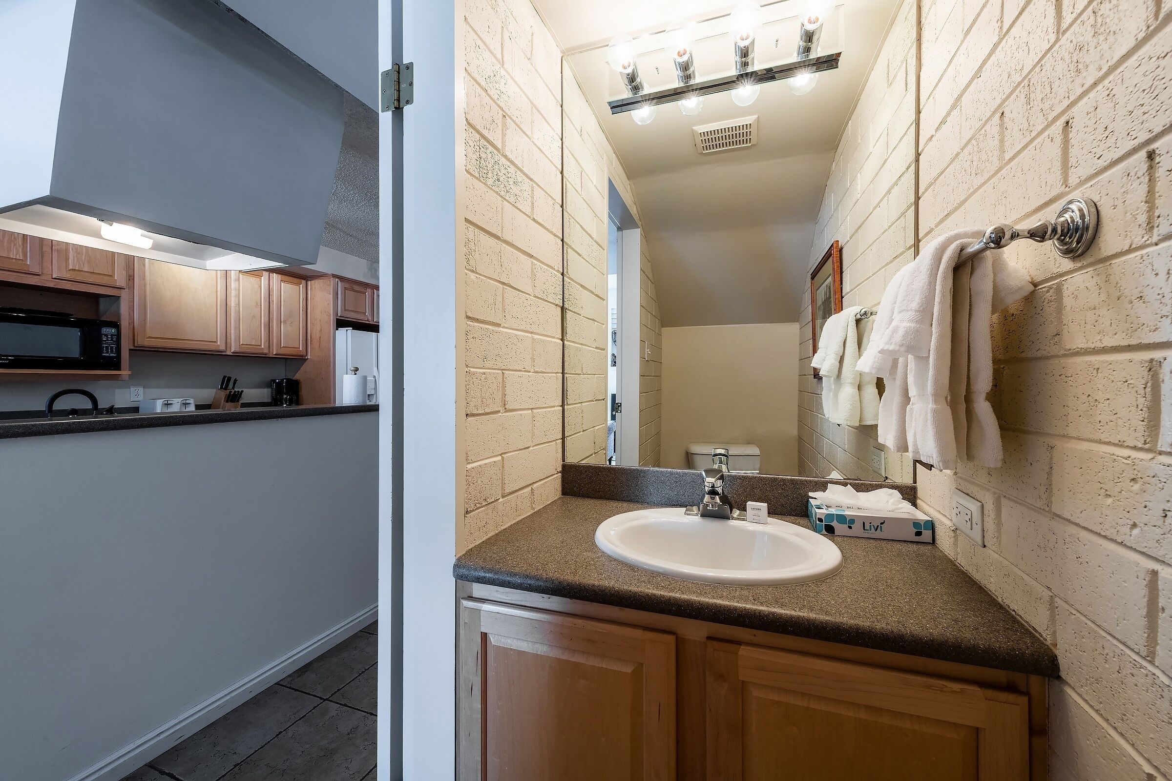 A modern kitchen with wooden cabinets, a microwave, and a sink.