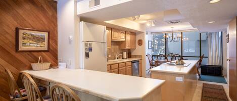 Una cocina moderna con armarios de madera, una isla grande y un comedor con sillas.