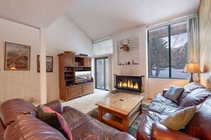 A cozy living room with a fireplace, leather sofas, a coffee table, and a bookshelf. - Park Avenue 3 Bedroom Condominiums (Park City)
