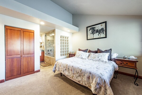 A bedroom with a large bed, wooden wardrobe, and a bathroom with a glass shower. - Park Avenue 3 Bedroom Condominiums (Park City)