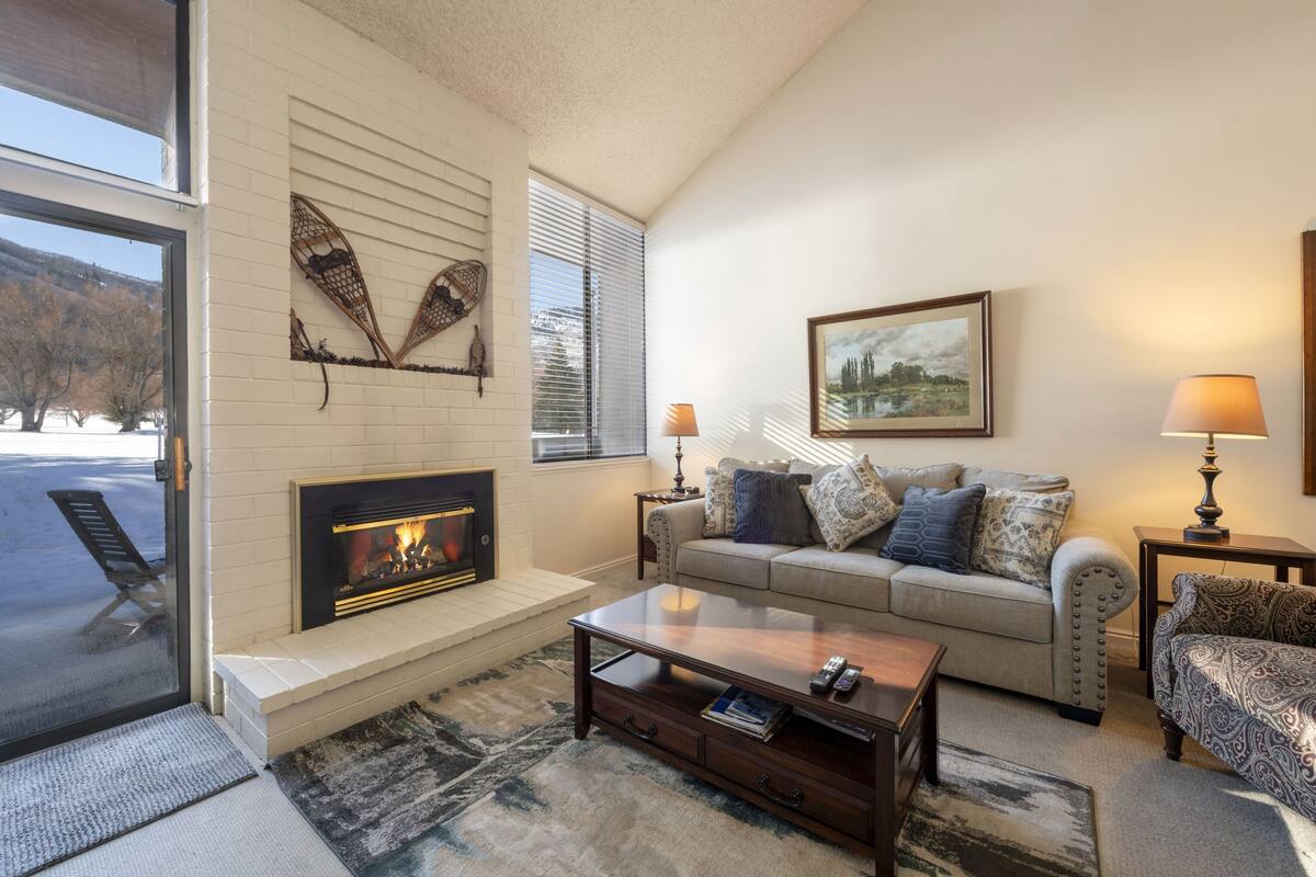 A cozy living room with a fireplace, a sofa set, and a coffee table.