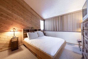 A bedroom with a wooden bed, bedside tables, a nightstand, a window with blinds, and a dresser. - Park Avenue 3 Bedroom Condominiums (Park City)