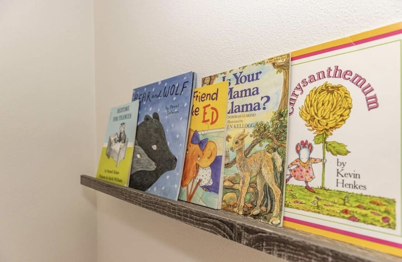 A shelf with four books titled 'Before the Bear and Wolf', 'Friend or Foe', 'Is Your Mama a Lama?', and 'Corysanthenum'.