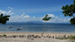 Una playa con cielos despejados, agua tranquila y un pequeño bote.
