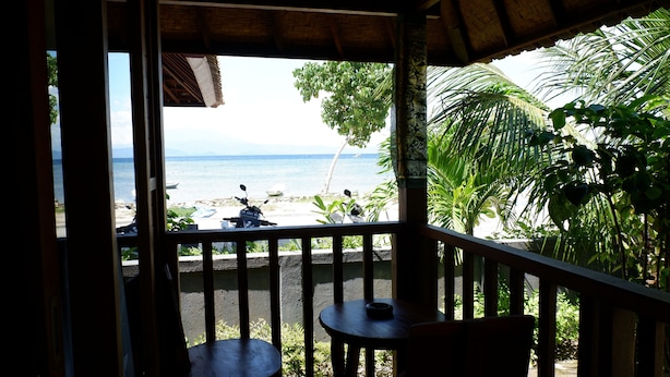 Un balcón de madera con vista a la playa y el océano.