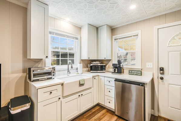A modern kitchen with white cabinetry, a stainless steel dishwasher, a built-in microwave, and a toaster.