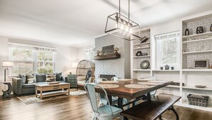 Un salon moderne avec un coin repas, comprenant un mur en briques, des étagères blanches et une table à manger en bois.