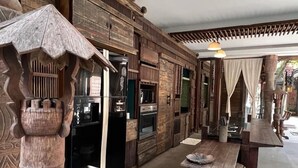Interior de madera tradicional con suelo de piedra, una mesa de madera y un banco.