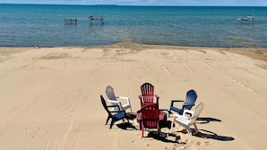 En strand med tre Adirondack-stolar och en gunga gjord av ett däck.