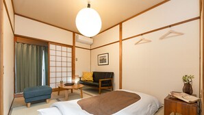 A traditional Japanese-style room with tatami flooring, a low wooden bed, a sofa, a small table, and a hanging light fixture. - Dongurian (Kyoto)