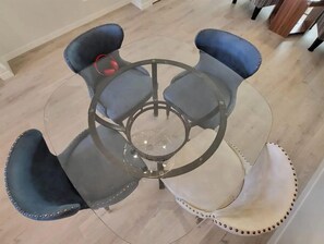 Four chairs surround a round table in a stylish room with a neutral color palette.