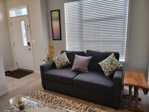 Relax in this inviting living space with a comfortable sofa, side table, and large window.