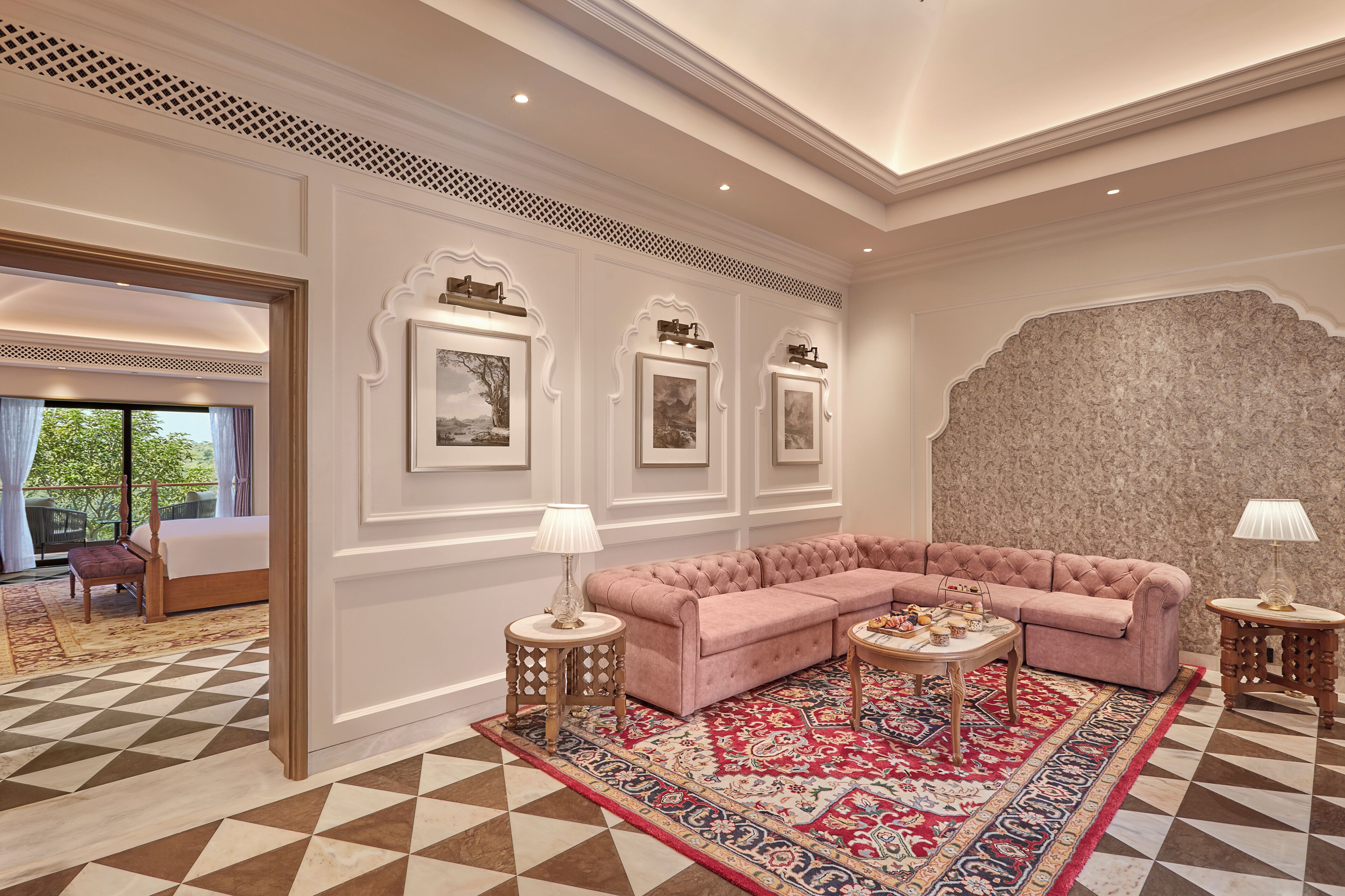 A luxurious living room with a pink sectional sofa, a patterned rug, and framed artwork on the walls.
