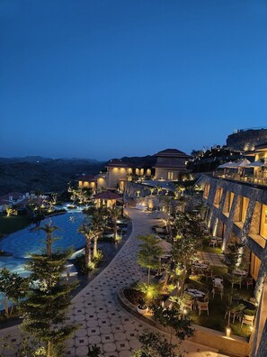 A resort with a pool, outdoor seating, and a view of the ocean at dusk.