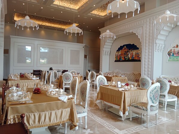 Un comedor lujoso con candelabros ornamentados, una elegante vajilla y arte tradicional.