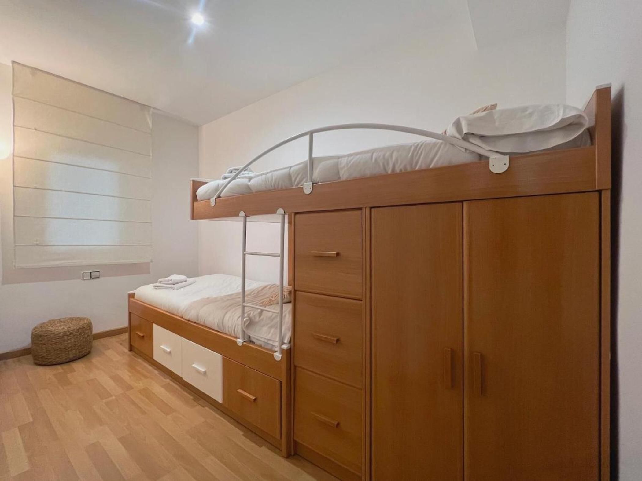 A bunk bed with a wooden frame and a wardrobe with multiple drawers.