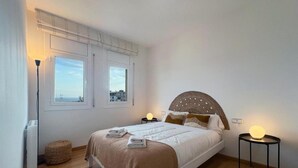 Une chambre à coucher avec un lit, deux tables de chevet, une lampe et une fenêtre donnant sur un beau paysage.