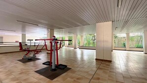 Une salle de sport spacieuse, dotée d’équipements d’exercice, de grandes fenêtres et d’un plafond haut.