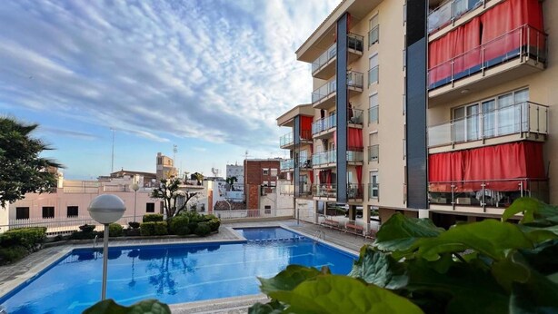 Une piscine offrant une vue dégagée sur les immeubles voisins, dont certains sont dotés de rideaux rouges.