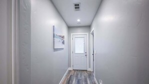A narrow hallway with a white door at the end, a small picture on the wall, and a light fixture on the ceiling. - Stylish Central San Jose 3B2B w/crib Free Parking (San Jose)