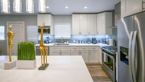 A modern kitchen with white cabinets, stainless steel appliances, and pendant lighting. - Stylish Central San Jose 3B2B w/crib Free Parking (San Jose)