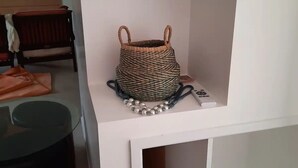 Een witte console tafel met een geweven mand en een kralenketting.