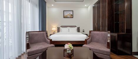 Ein Hotelzimmer mit einem Bett, zwei Sessel, einem Couchtisch und einem großen Kleiderschrank.