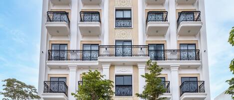 Ein mehrgeschossiges Hotel im klassischen Stil, mit Balkonen und aufwendigen Geländern, einem zentralen Eingang mit Stufen und der Beschriftung "Florence Hotel".