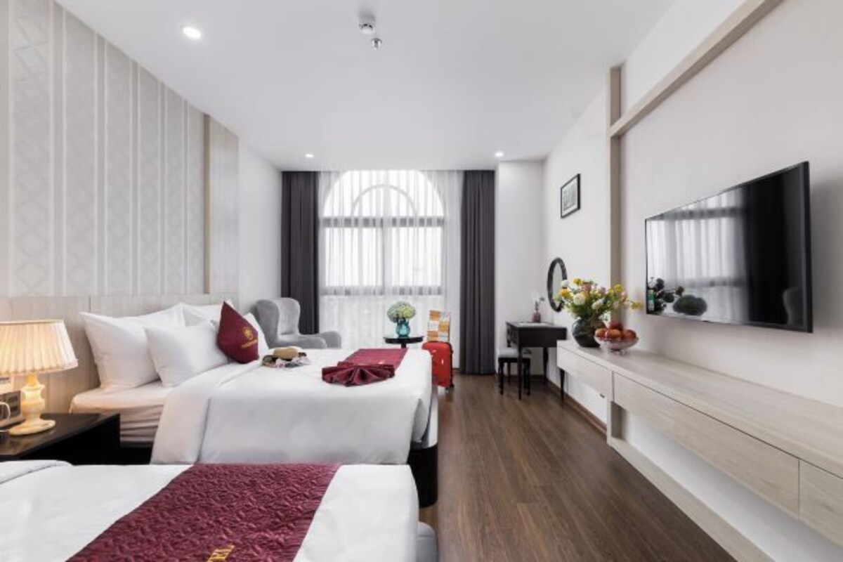 Ett hotellrum med två sängar, ett skrivbord, en TV och ett stort fönster.