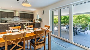 A modern kitchen with a dining area, large sliding glass doors to an outdoor patio, and a view of greenery. - Haigerach Holiday Apartment with Private Terrace and Wi-Fi (Gengenbach)