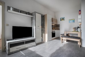 A modern kitchen with a built-in oven, a dining table, and a bench.