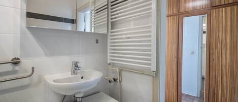 A bathroom with a white sink, mirror, and towel rack.