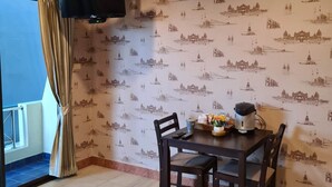 A dining area with a table, chairs, and a television mounted on the wall. - Kamala Cool 2 (Kamala)