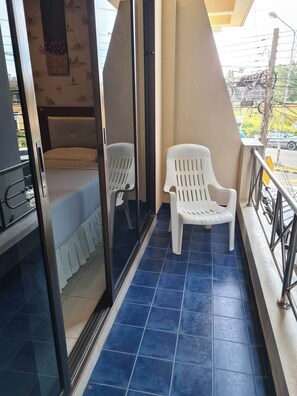 A balcony with blue tiles, a white plastic chair, and a white plastic bench. - Kamala Cool 2 (Kamala)