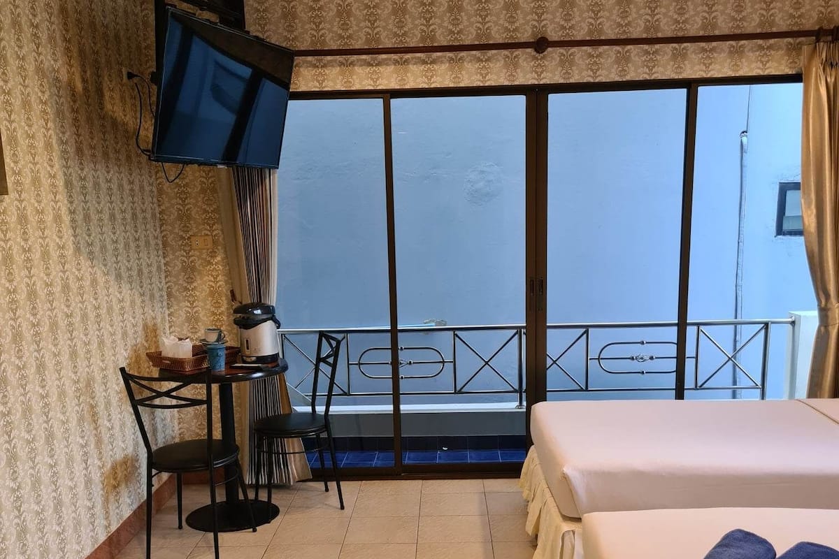 Quarto de hotel com cama, escrivaninha, cadeira, televisão e varanda com vista.