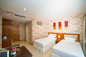 A hotel room with two beds, a wooden wardrobe, a desk with a chair, and a small table with a vase of flowers. - Kamala Cool 2 (Kamala)