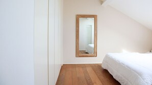 A bedroom with a wooden floor, a white bed, and a mirror on the wall. - Castello Charme Style House (Milano)