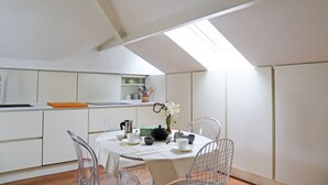 A modern kitchen with white cabinets, a skylight, and a dining area with a table set for two. - Castello Charme Style House (Milano)