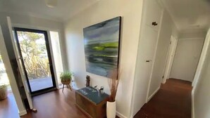 Un corridoio con pavimento in legno, una pianta in vaso e un quadro appeso al muro.