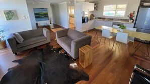 Un soggiorno moderno con un divano, un piccolo tavolo in legno e un tappeto bianco e nero.