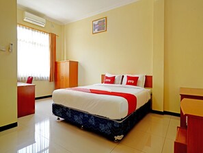 Une chambre d’hôtel avec un lit, un bureau, une armoire et une fenêtre avec des rideaux.