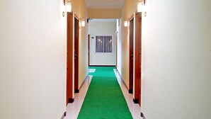 Ein Korridor mit grünem Teppich, Holztüren und Wandleuchten.