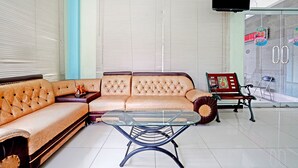 Ein Wohnzimmer mit einer Couch, einem Glastisch, einem Fernseher und einer Bank.