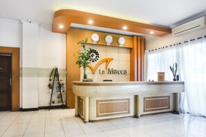 Un comptoir d’accueil avec une horloge, une enseigne indiquant « Réception » et une plante.