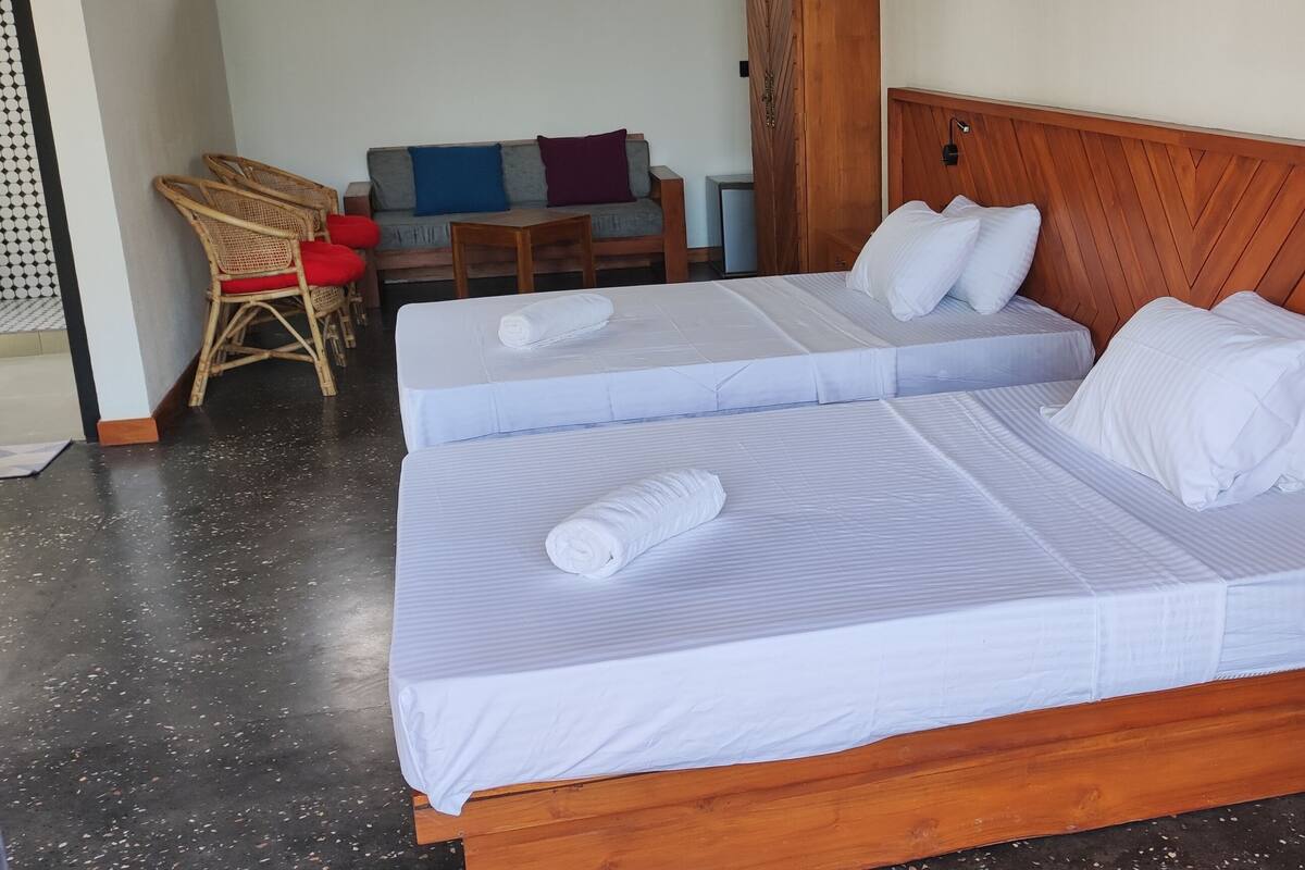 A double bed with white linens, a wooden headboard, and a nightstand.