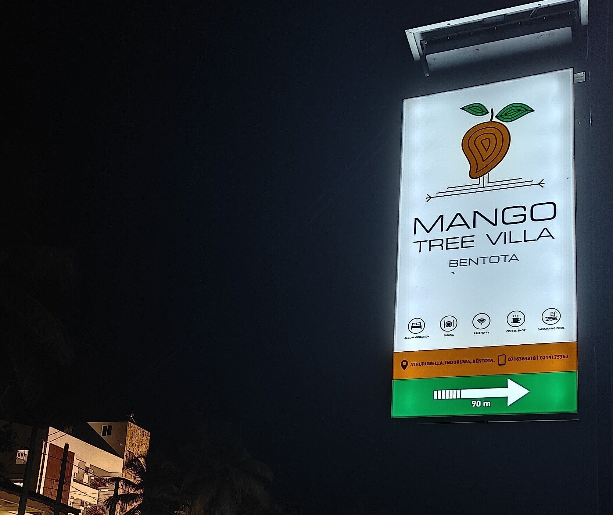 A sign for Mango Tree Villa in Bentota, indicating amenities like accommodation, dining, free Wi-Fi, a coffee shop, and swimming pools.