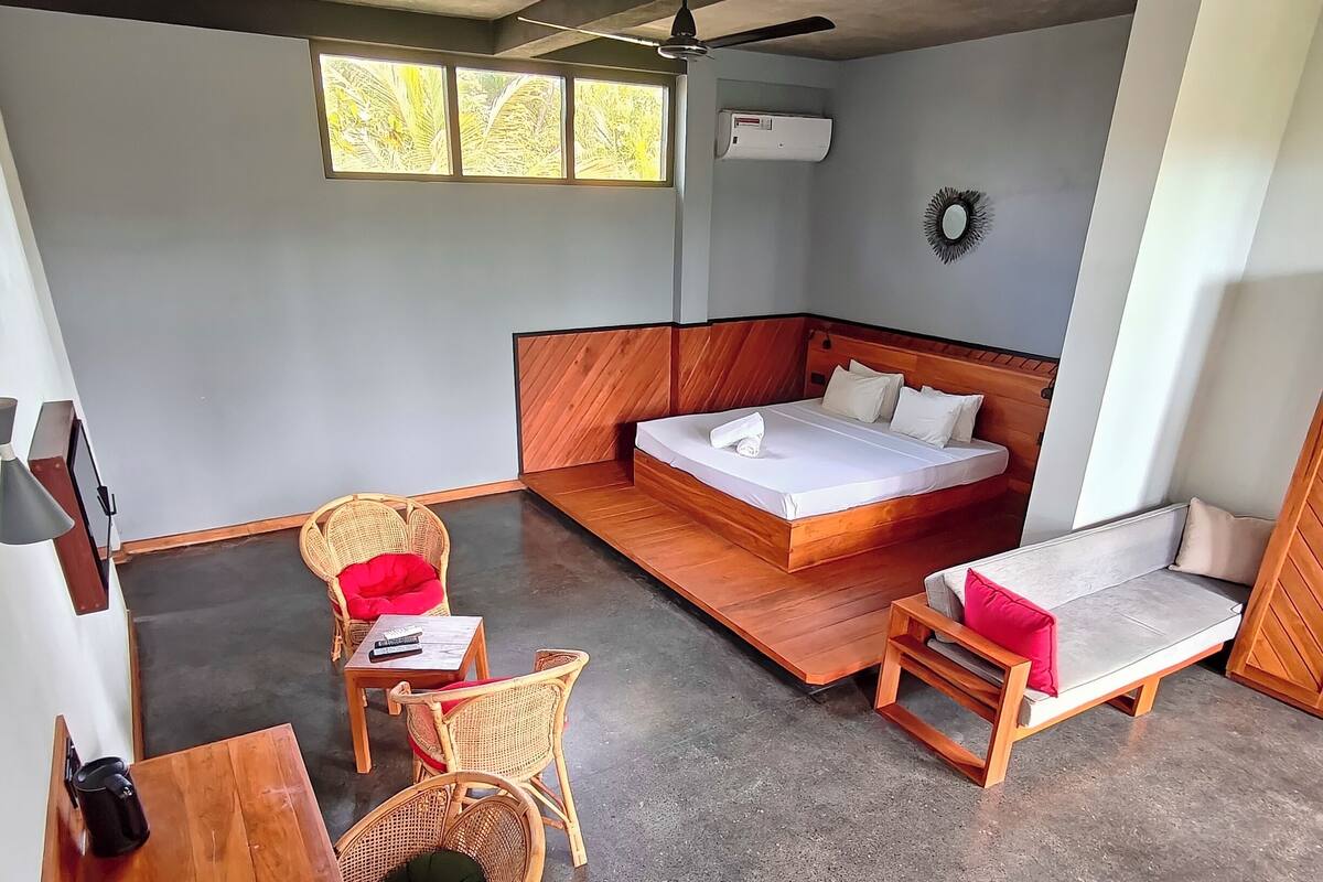 A room with a bed, a desk, a chair, and a small table.